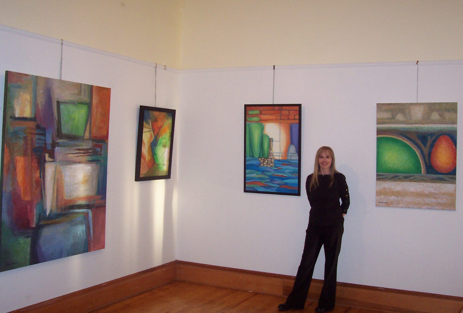 A woman standing in front of three paintings.