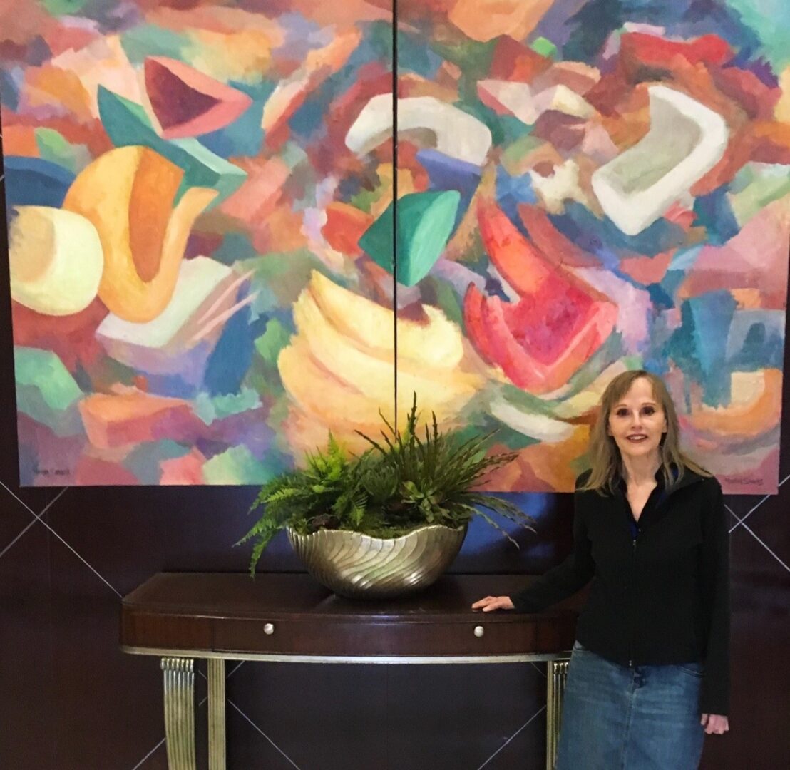 A woman standing in front of a painting with a plant.