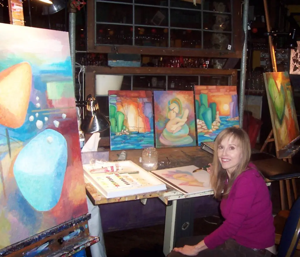 Local Fine Art For Sale: A talented woman captivates onlookers as she sits gracefully at an easel, passionately creating mesmerizing artworks that adorn the walls of this enchanting art gallery.