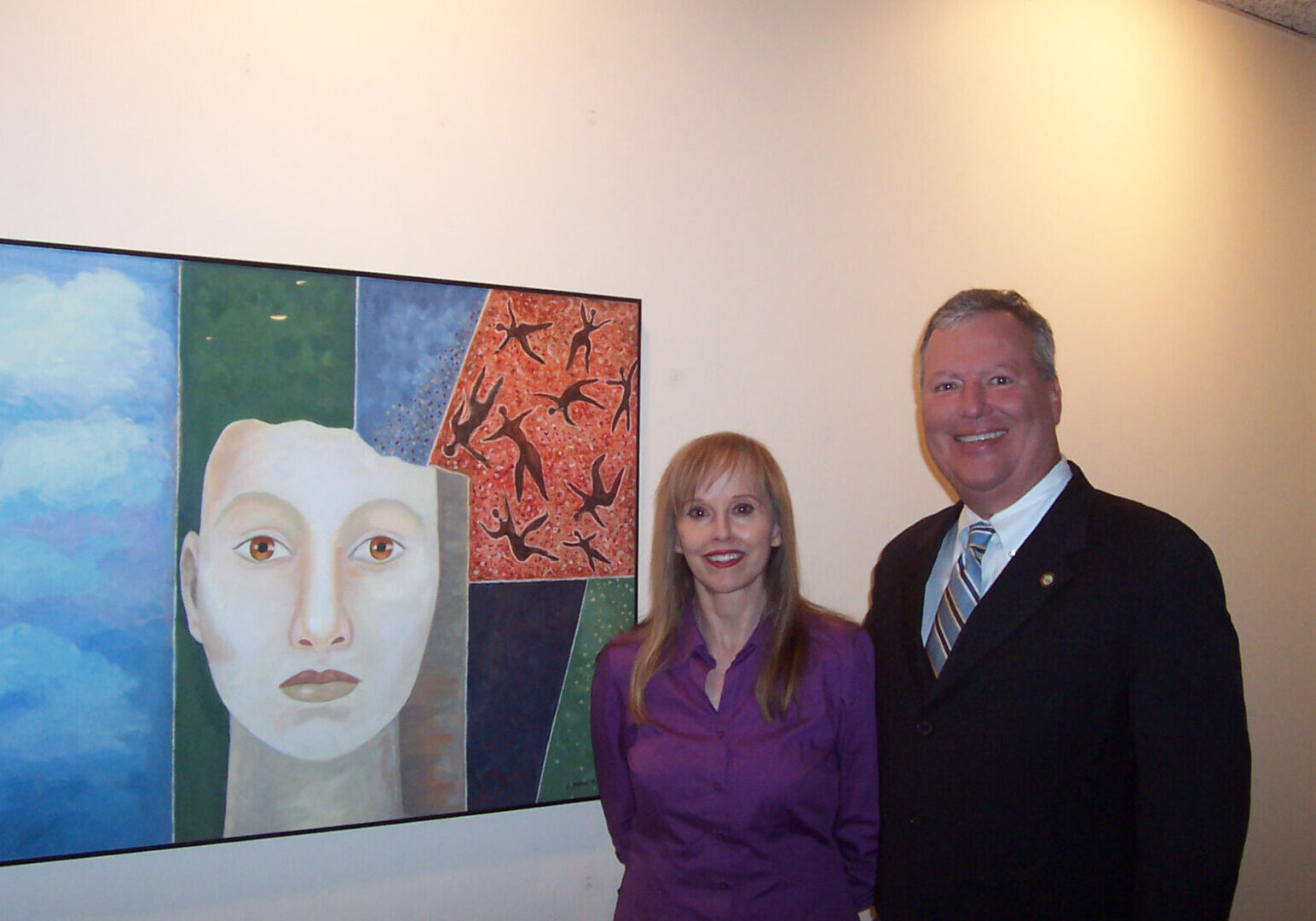 A man and woman standing in front of a painting.