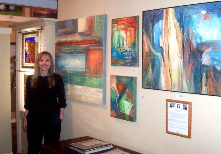 A woman standing in front of some paintings